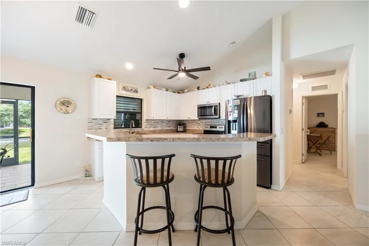 Kitchen featuring white cabinetry, stone-finish countertops, stainless steel appliances, and a tiled backsplash