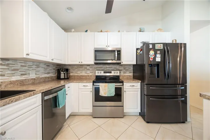 Kitchen featuring white cabinetry, stainless steel appliances, a mosaic tile backsplash, textured countertops, and diagonal tile flooring