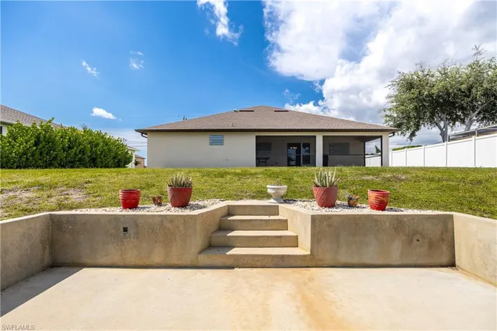 Concrete patio area with a multi-level retaining wall, integrated steps, and a landscaped upper tier