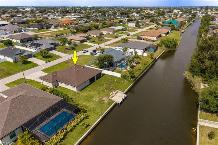 Waterfront property featuring a private boat dock, screened lanai, manicured lawn, and lush landscaping