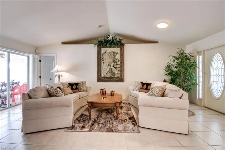 Living room featuring healthy amount of natural light, lofted ceiling, and light tile patterned floors