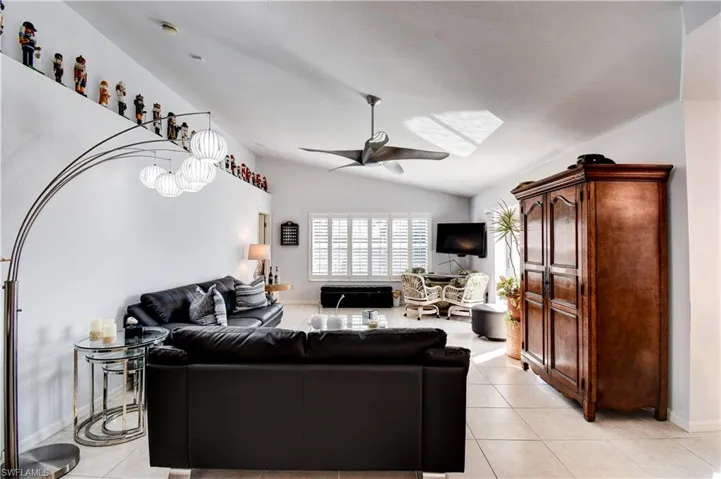 Living room featuring ceiling fan, light tile patterned flooring, and lofted ceiling