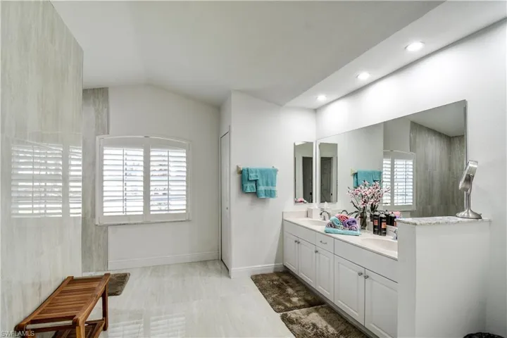 Full bath featuring double vanity, lofted ceiling, and walk in shower