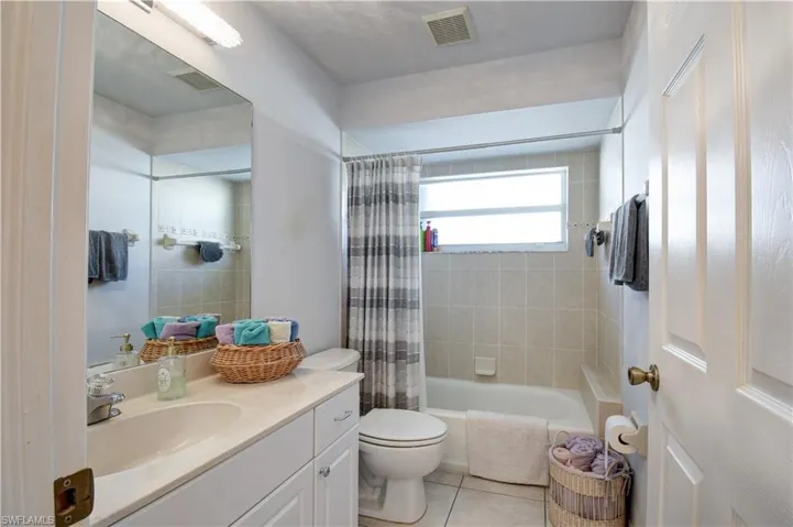 Full bathroom with vanity, shower / tub combo, and light tile patterned floors