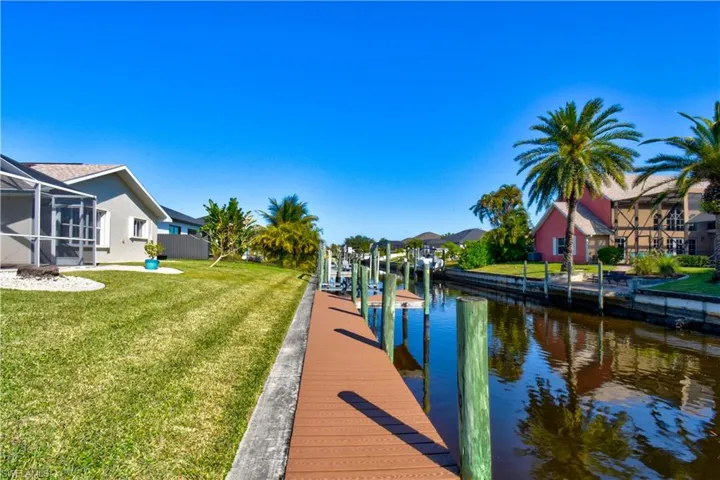 Dock with a lanai, a water view, a lawn, a sunroom, and a residential view
