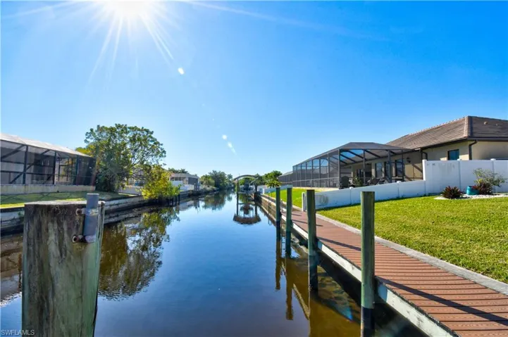 Dock area with a sunroom, a lanai, a water view, and a yard