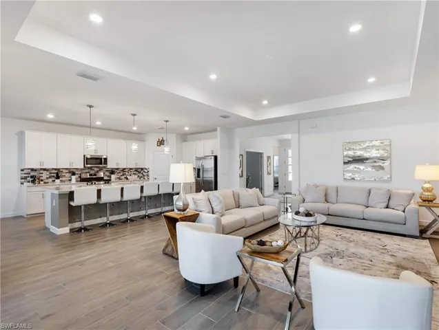 Living room with a tray ceiling and light wood-type flooring