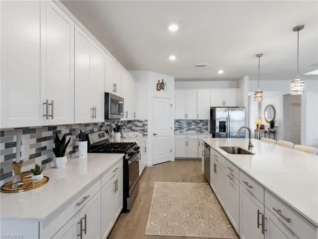 Kitchen featuring light hardwood / wood-style floors, stainless steel appliances, sink, and white cabinets