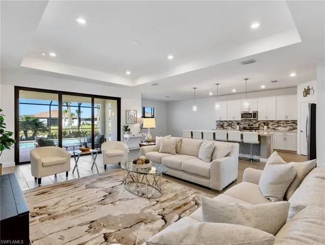 Living room with a tray ceiling and light wood-type flooring