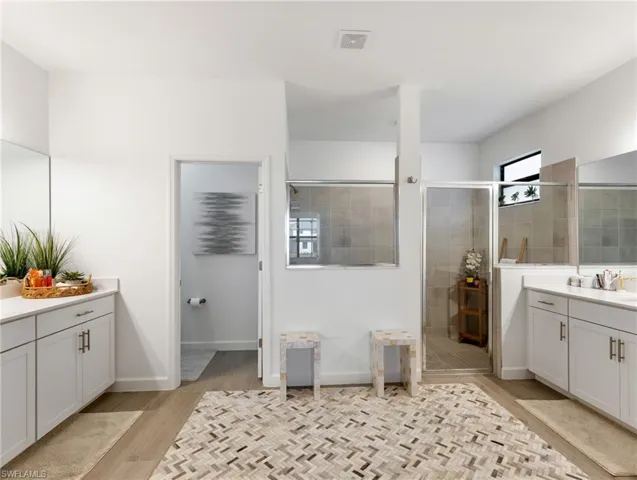 Bathroom featuring vanity, hardwood / wood-style flooring, and a shower with door