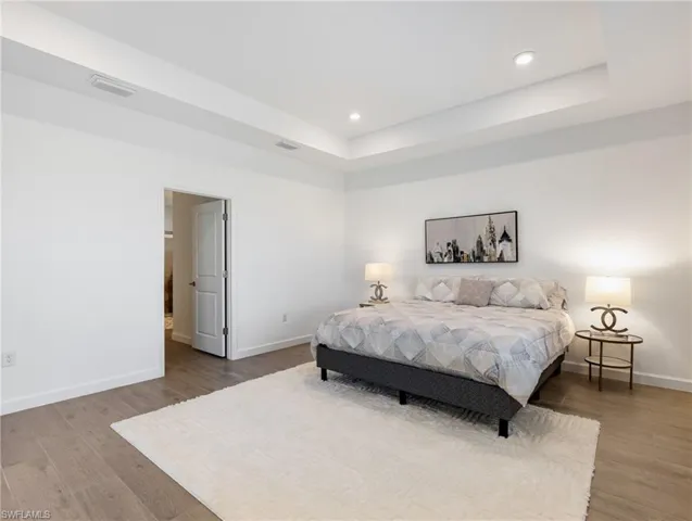 Bedroom featuring hardwood / wood-style flooring and a raised ceiling