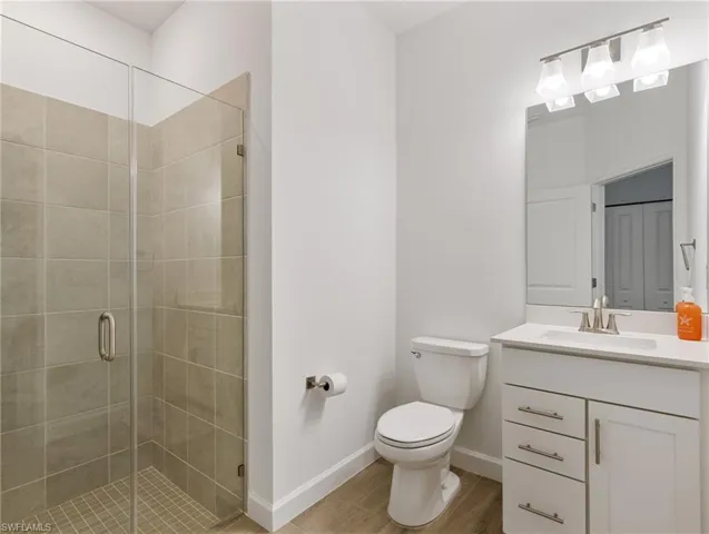 Bathroom with vanity, toilet, a shower with shower door, and hardwood / wood-style floors