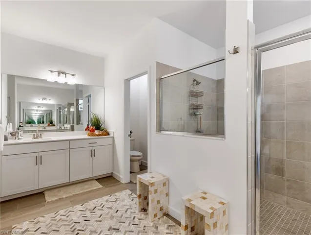 Bathroom featuring a shower with door, toilet, hardwood / wood-style flooring, and vanity