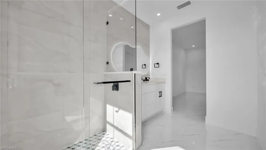 Full bath with vanity, recessed lighting, a marble finish shower, and light marble finish floors