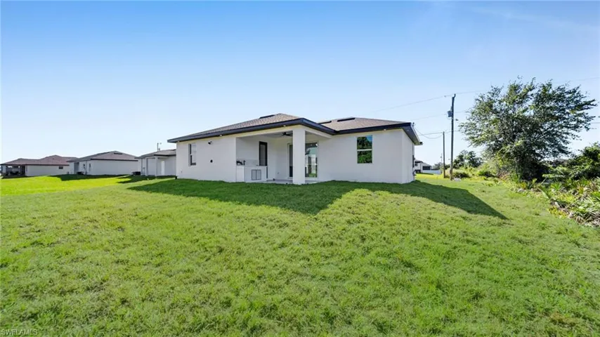 Back of property featuring stucco siding, a patio, a lawn, and ceiling fan