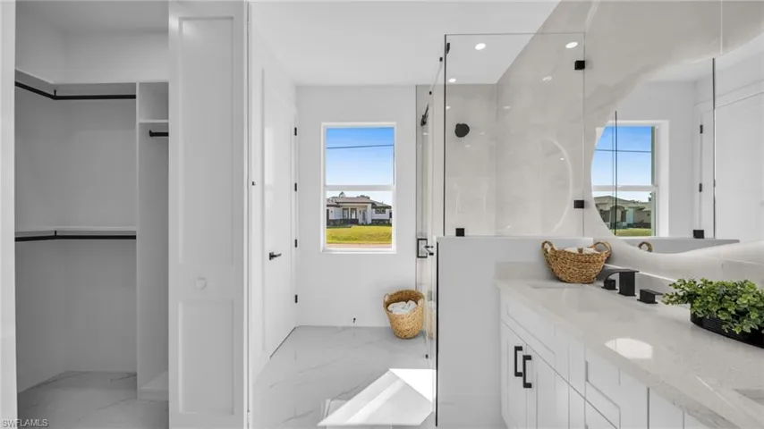Full bathroom featuring a spacious closet, a marble finish shower, double vanity, light marble finish flooring, and recessed lighting