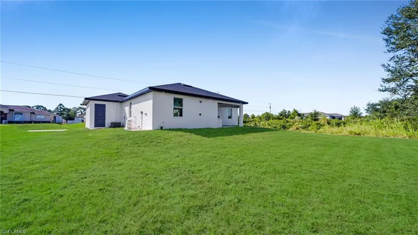 Back of house with a yard and stucco siding