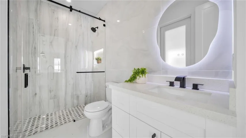 Bathroom featuring tile walls, vanity, and a marble finish shower