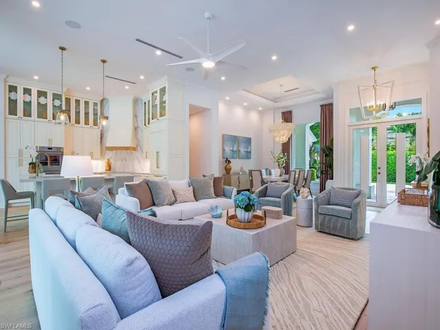 Open-concept living area featuring light wood-finish flooring, recessed lighting, and a tray ceiling