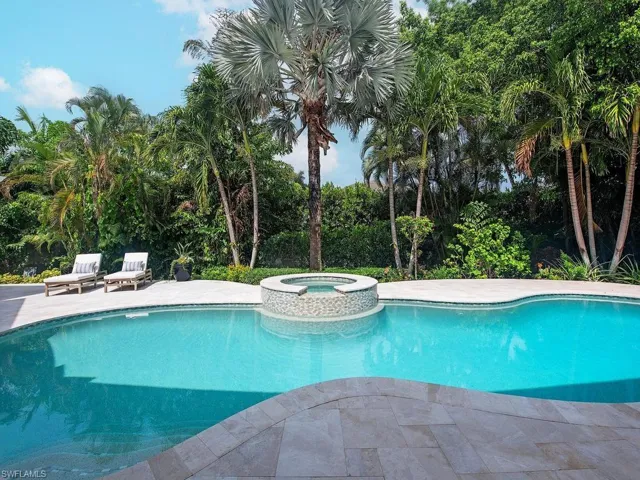 Freeform swimming pool with an integrated circular spa featuring mosaic tile detailing