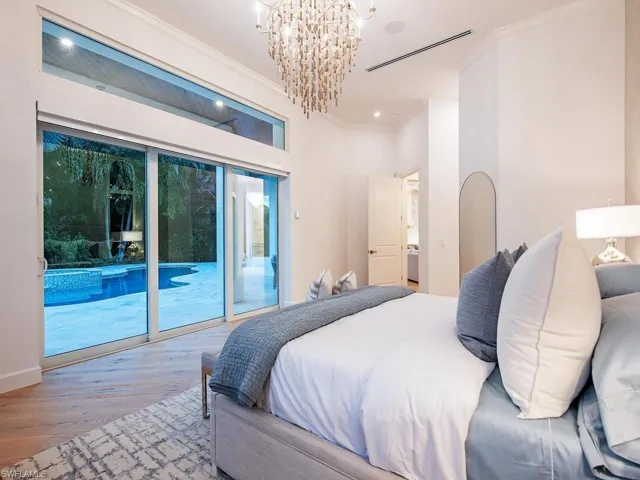 Bedroom featuring a large multi-panel sliding glass door, a transom window, wood-finish flooring, a contemporary chandelier, and recessed lighting