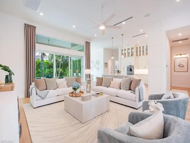 Expansive living area featuring light wood-finish flooring, a large area rug, and recessed ceiling lighting