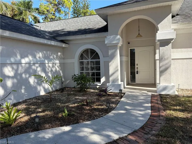 Doorway to property with roof with shingles and stucco siding