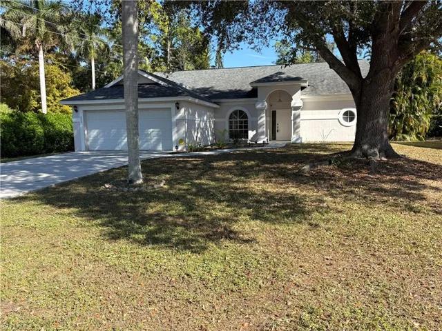 Ranch-style house featuring concrete driveway, a front yard, a shingled roof, and an attached garage