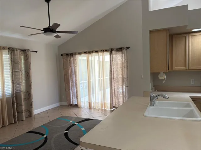 Kitchen with light countertops, lofted ceiling, light tile patterned floors, and a ceiling fan