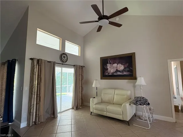 Living area featuring high vaulted ceiling, light tile patterned floors, and a ceiling fan