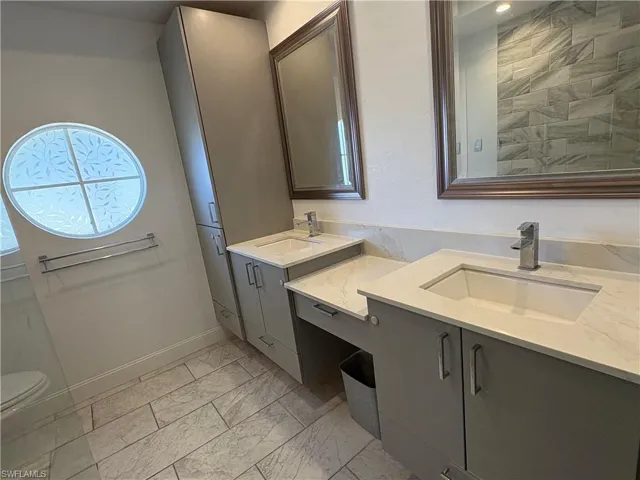 Full bathroom with two vanities and light marble finish floors