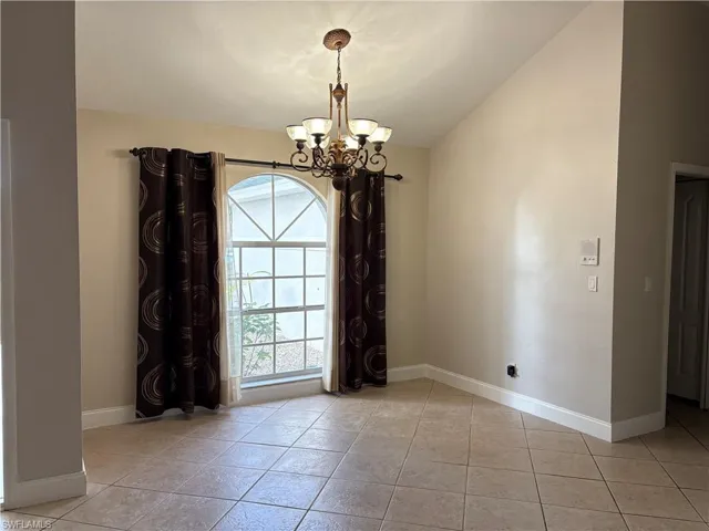 Empty room featuring a chandelier and light tile patterned floors