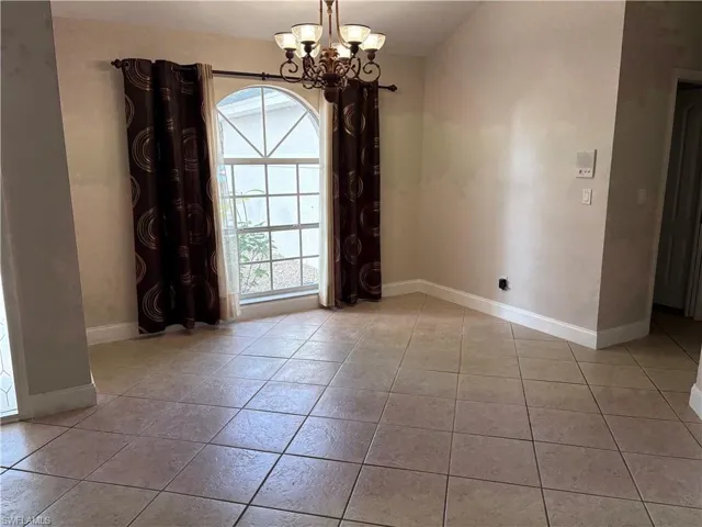 Unfurnished dining area featuring a chandelier and light tile patterned flooring