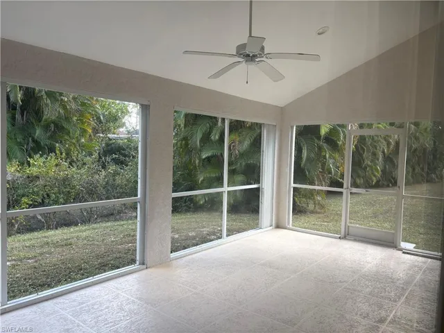 Unfurnished sunroom featuring a ceiling fan, lofted ceiling, and plenty of natural light