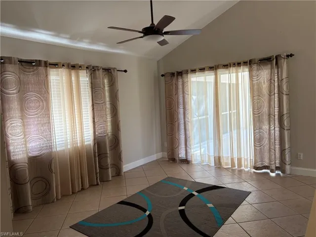 Exercise room with light tile patterned floors, lofted ceiling, and ceiling fan