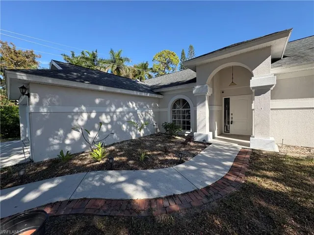 Entrance to property with stucco siding and a shingled roof