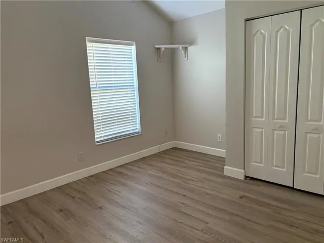 Unfurnished bedroom featuring lofted ceiling, light wood-type flooring, and a closet