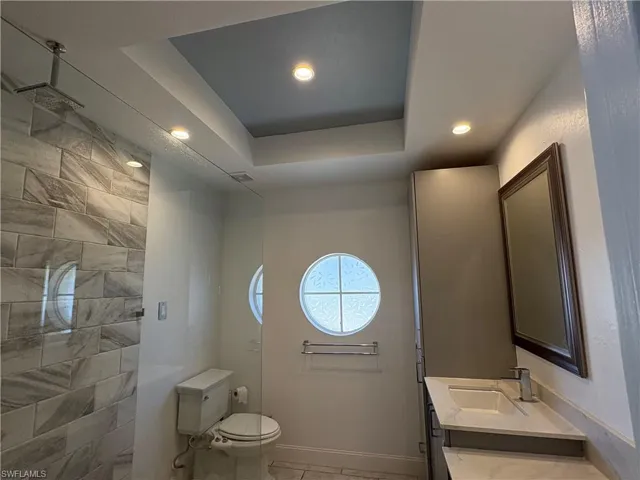 Full bath with a raised ceiling, vanity, recessed lighting, and walk in shower