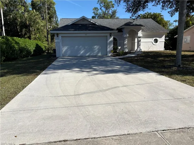 Ranch-style home with concrete driveway, roof with shingles, an attached garage, and a front lawn