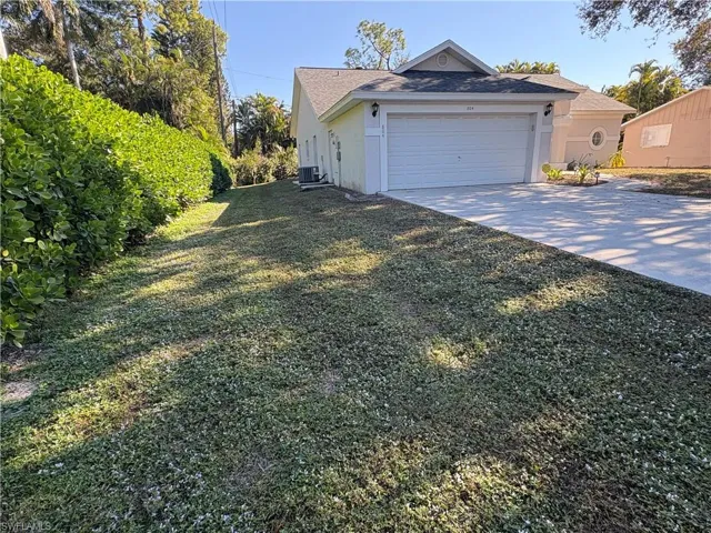 View of home's exterior featuring driveway, stucco siding, a yard, and a garage