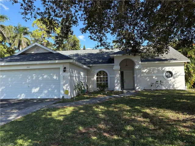 View of front facade featuring roof with shingles, a front lawn, concrete driveway, stucco siding, and an attached garage