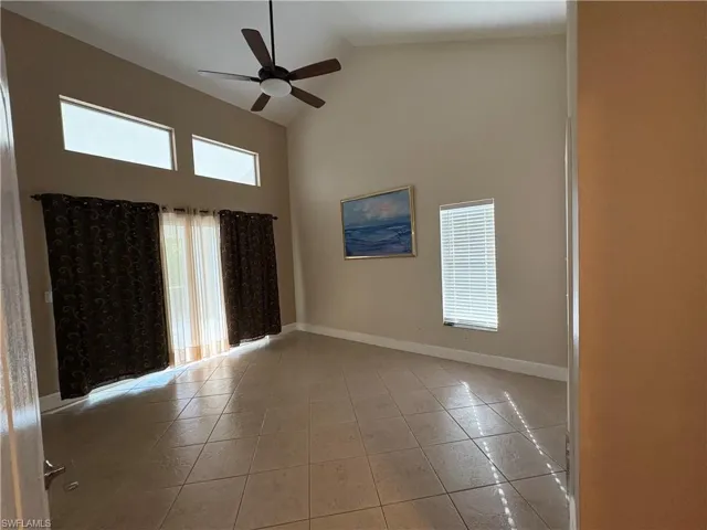 Unfurnished room with high vaulted ceiling, a ceiling fan, and light tile patterned flooring