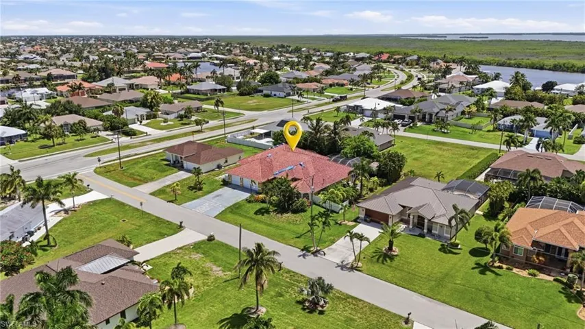 Expansive corner lot featuring a paver driveway, mature palm trees, and a red tile roof