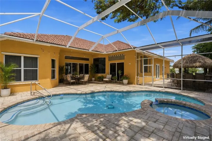 Screened outdoor living area featuring a freeform pool, integrated spa, and pavers