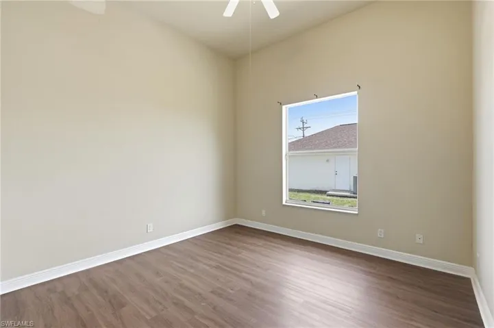 Spacious room featuring wood-finish flooring, vaulted ceiling, and a ceiling fan
