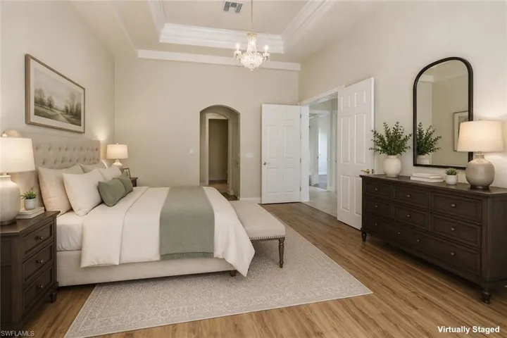Spacious room featuring wood-finish flooring, a coffered ceiling, and an arched doorway
