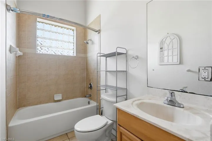 Full bathroom featuring a single vanity, built-in bathtub with shower, and tile surround