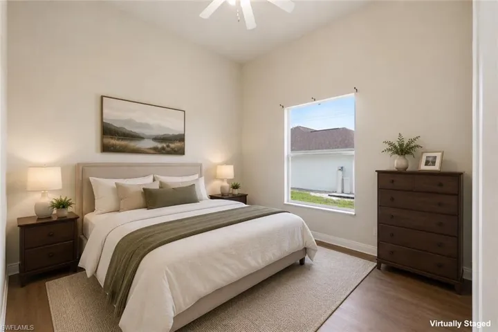 Bedroom featuring vaulted ceilings, wood-finish flooring, a ceiling fan, and a large window with a white frame