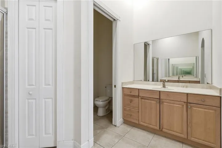 Dual-sink vanity with light wood cabinetry, a light-toned countertop, and a large wall-mounted mirror