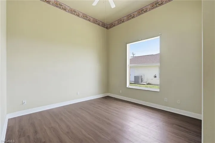 Spacious room featuring wood-finish flooring, light-toned walls, and a large window